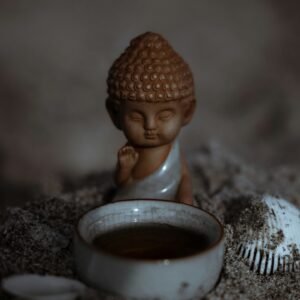 a small buddha statue sitting next to a bowl of soup